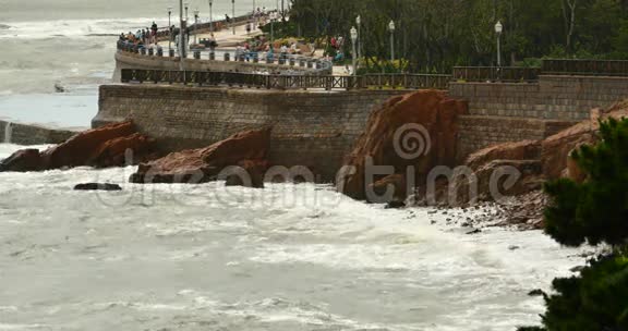 海浪冲刷大坝人们在岸上海洋海水和沿海岩石浪涌海岸视频的预览图