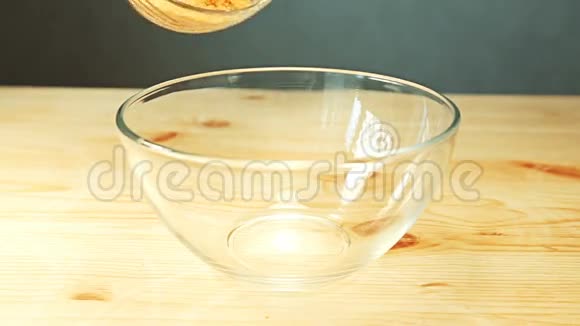 面包屑和香料混合在一起倒入厨房餐桌木制表面的玻璃碗中视频的预览图