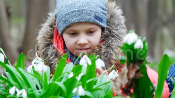 一个美丽可爱的小女孩喜欢在春天的森林里绽放的雪花视频的预览图