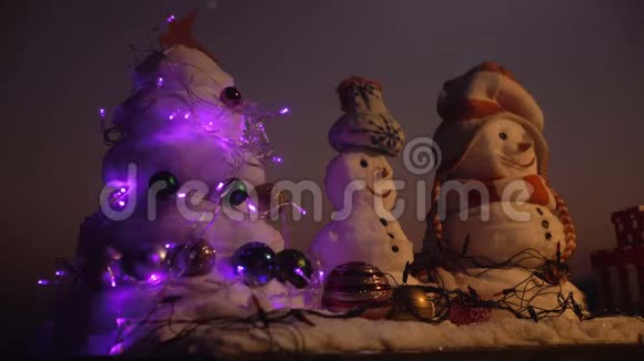 寒假庆祝理念雪人带着笑脸戴着帽子在傍晚的风景日落时的雪雕视频的预览图