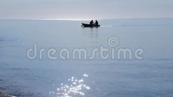 在清晨的阳光下船上的渔民们漂浮在岸边视频的预览图