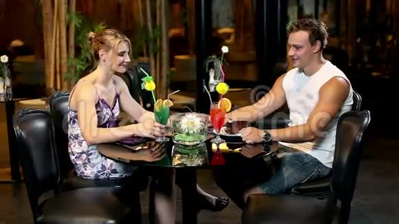 一对年轻夫妇在游泳池里喝鸡尾酒和蛋糕视频的预览图