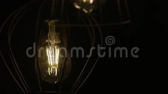 灯泡自然地在电线上移动灯在黑色背景上摆动慢动作视频的预览图