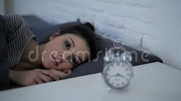 一个年轻迷人的西班牙裔女性在压力和失眠中心烦意乱躺在床上焦虑试图睡觉侧面的平底锅拍摄视频的预览图