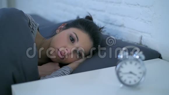 一个年轻迷人的西班牙裔女性在压力和失眠中心烦意乱躺在床上焦虑试图睡觉侧面的平底锅拍摄视频的预览图