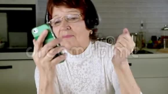 一位老年妇女从电话里用耳机听音乐积极地做手势跳舞视频的预览图