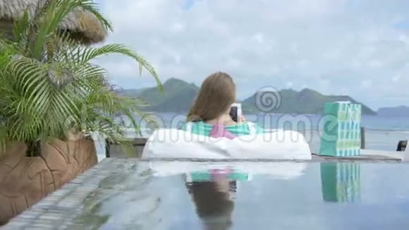年轻漂亮的女人在度假时坐在休息室里用数码平板电脑视频的预览图