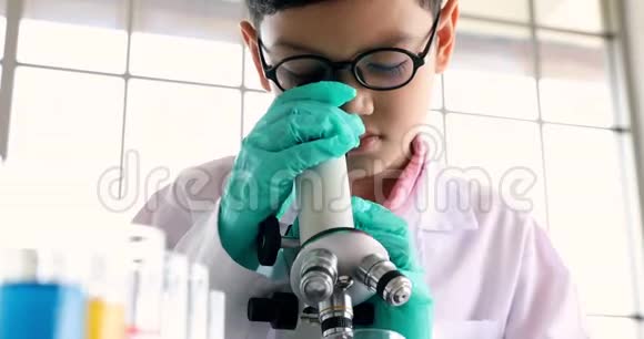在实验室里男孩透过显微镜看视频的预览图