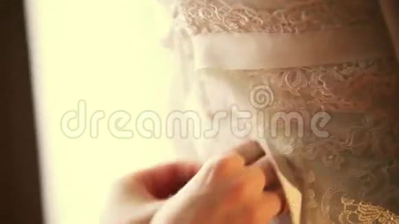 女人把丝带系在花边婚纱的背面给新娘庆祝日结婚暖色调视频的预览图