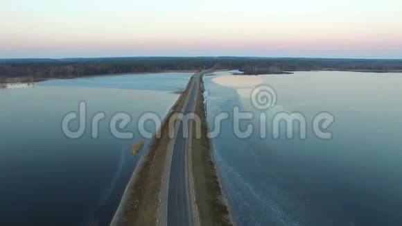 4K日落时分在冰冻的水中飞越公路鸟瞰视频的预览图