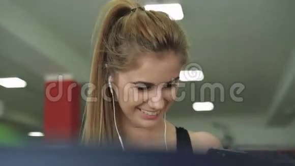 跑步机上漂亮的金发女郎用电话听音乐4k视频的预览图