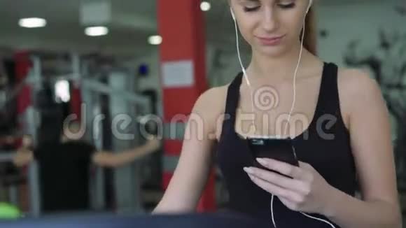 跑步机上漂亮的金发女郎用电话听音乐4k视频的预览图
