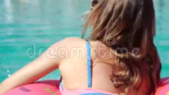 年轻时尚的千禧女孩在洒满甜甜圈的游泳池节日派对酒店海滩上活动中微笑着视频的预览图