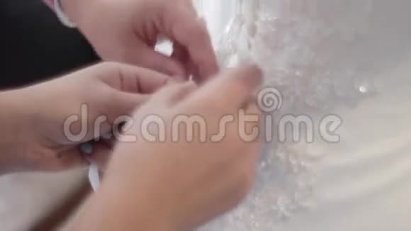 婚纱后面的特写新娘帮着穿衣服新娘为婚礼做准备视频的预览图