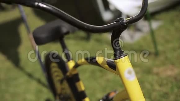 观看黑色和黄色创意自行车停留在绿草上夏季节日方向盘视频的预览图
