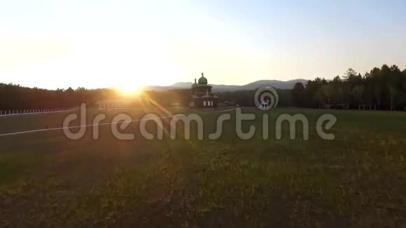 在阳光明媚的夏日傍晚在田野上教堂俄罗斯布里亚蒂亚乌兰乌德的鸟瞰图视频的预览图