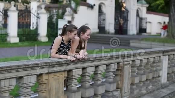 两个年轻的女孩站在石栅栏附近花时间交谈视频的预览图