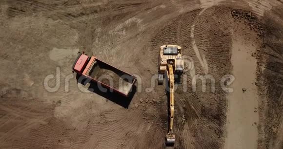 挖掘机的鸟瞰将沙子倒入卡车视频的预览图