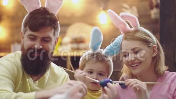 父亲母亲和孩子在画复活节彩蛋幸福的家庭正在为复活节做准备可爱的小男孩穿着视频的预览图