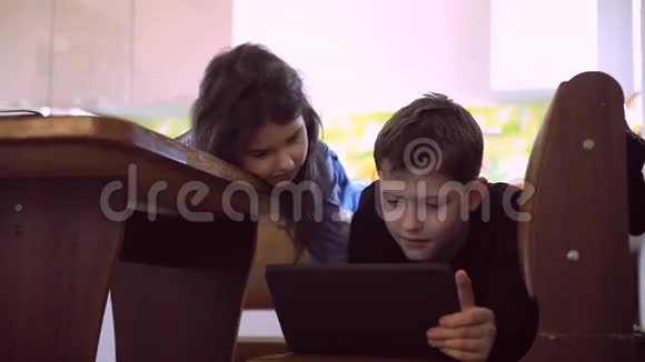 有平板电脑的青少年男孩和女孩躺在沙发上浏览互联网视频的预览图
