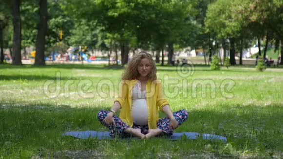 美丽的孕妇在户外做产前瑜伽怀孕期间的运动健身和健康生活方式视频的预览图