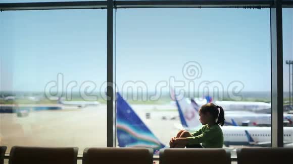 儿童在机场窗口附近看飞机等待飞行时间视频的预览图