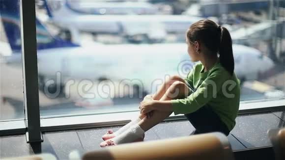 儿童在机场窗口附近看飞机等待飞行时间视频的预览图