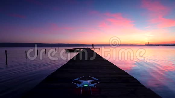 空中无人机飞越小码头在湖边划船日落视频的预览图