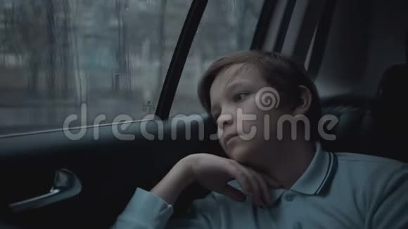 伤心不幸的小男孩在雨天开车穿过城市视频的预览图