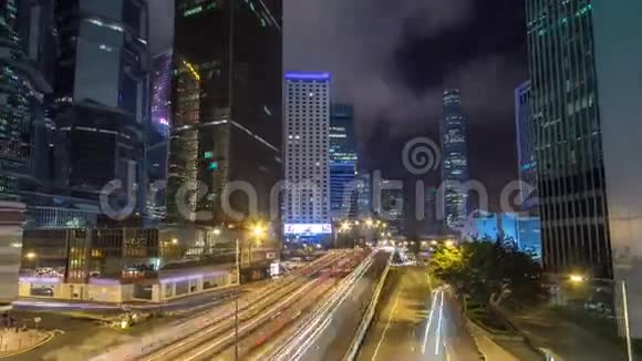 香港商业区夜间时间推移公司大楼在后面繁忙的交通穿过主干道视频的预览图