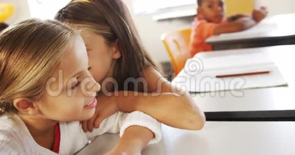 女学生在教室里对着她的朋友耳语视频的预览图