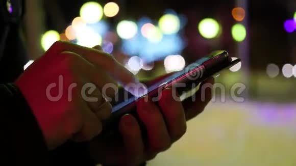 在城市的夜晚冬天的时候男人用智能手机短信特写视频的预览图