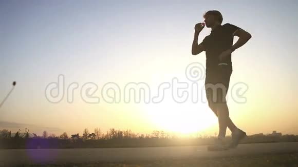 晚上跑步者在广角日落景观上喝水视频的预览图