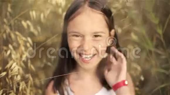 日落时一个小女孩在一片高大草地上的肖像视频的预览图