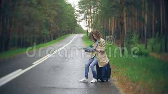 年轻漂亮的女人站在路上一个手提箱放在桌子上上面写着大海视频的预览图