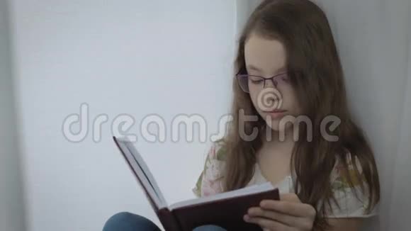 戴眼镜的严肃的小女孩勤奋地在窗口做作业视频的预览图