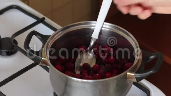 一个人把一勺冰冻的蔓越莓拌在平底锅里为棉花糖准备土豆泥视频的预览图
