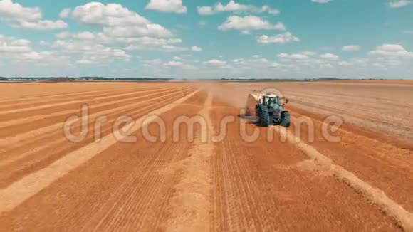 空中视野飞越麦田联合收割机拖拉机和拖车在夏日生产成堆的小麦视频的预览图