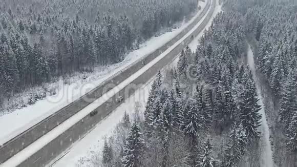 道路在冬季森林与驾驶汽车在降雪空中全景消失的角度视频的预览图