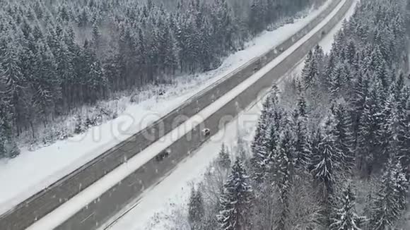 道路在冬季森林与驾驶汽车在降雪空中全景消失的角度视频的预览图