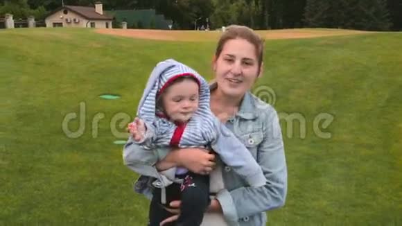 美丽的微笑妈妈抱着小儿子在公园散步视频的预览图