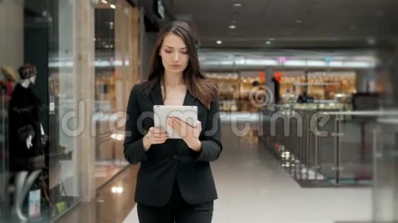 微笑着成熟的职业女商人在办公室手持数码平板电脑机场或购物场所的黑发女人视频的预览图