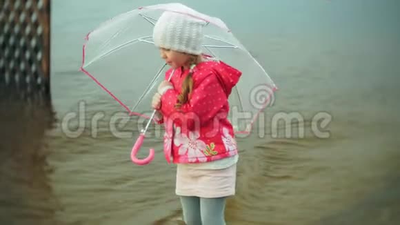 小美丽的女孩带着雨伞在雨中玩耍沿着海岸散步视频的预览图