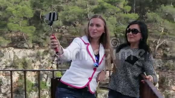 两位年轻的美女在公园的街上用智能手机拍照视频的预览图