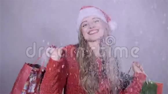 快乐的圣诞老人女孩拿着购物袋在演播室里享受着降雪视频的预览图