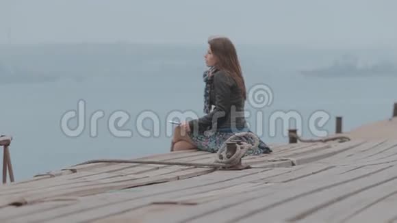 靠近一个坐在码头上的可爱女孩视频的预览图