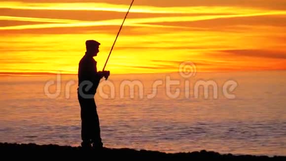 渔人剪影海上日落时的钓鱼竿视频的预览图
