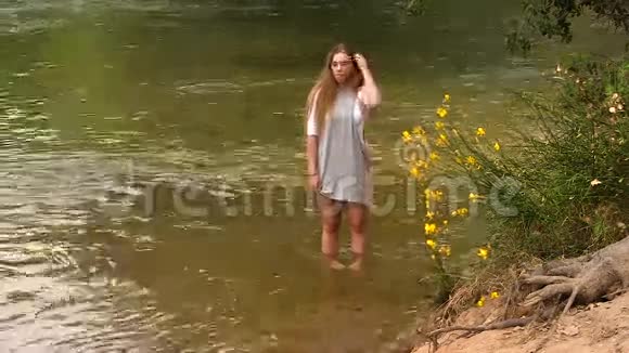 漂亮的白人少女穿着灰色衣服站在河里视频的预览图