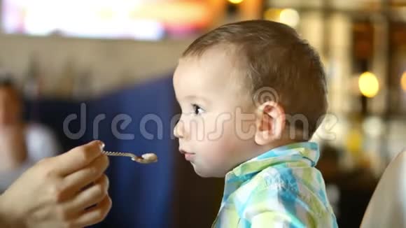 妈妈在一家餐馆里用婴儿勺子给婴儿食物一个孩子心甘情愿地吃4k视频的预览图