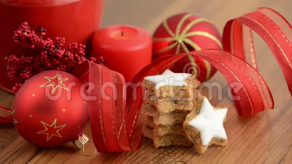 在圣诞节的时候点燃了一支蜡烛前面有一个蛋糕架上面有肉桂饼干丝带圣诞球视频的预览图